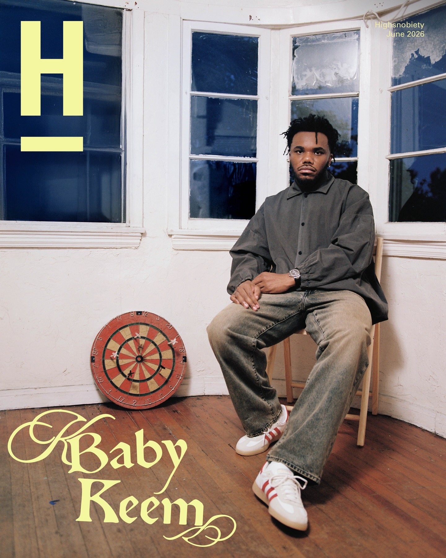 Baby Keem x Highsnobiety cover, seated on a wooden chair by bay windows, dartboard on the floor